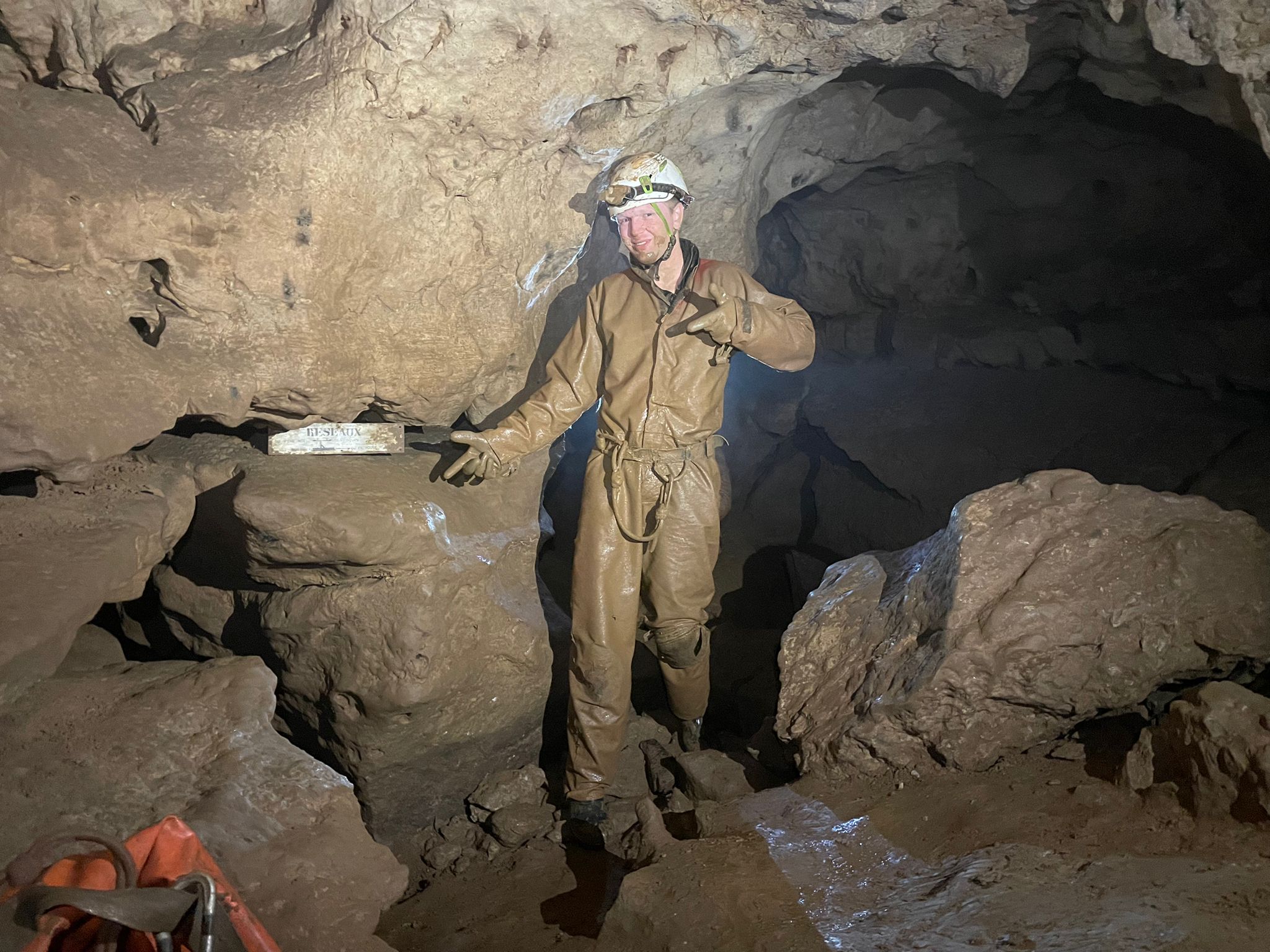 Caver exploring a muddy cave