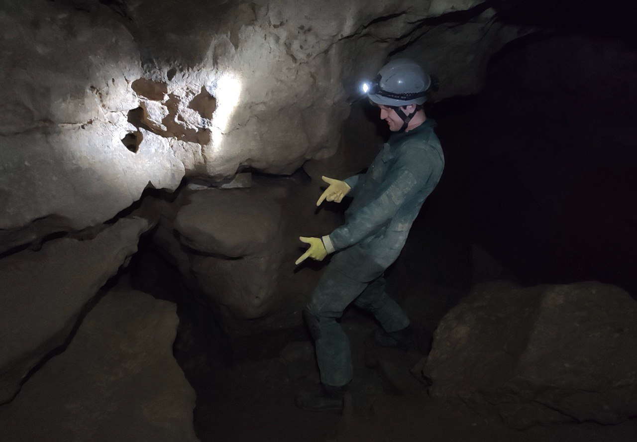 Clean caver exploring a muddy cave